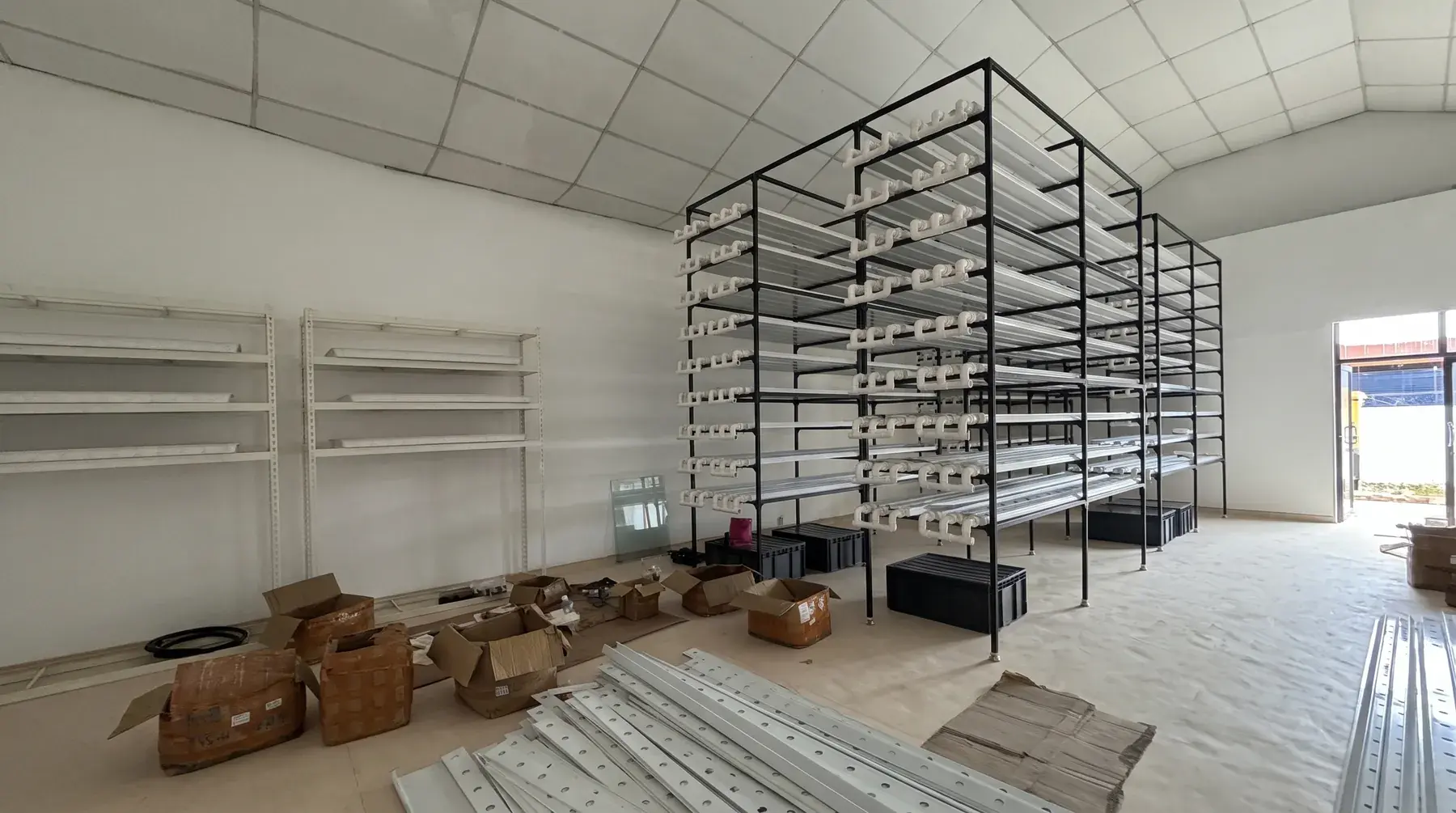An indoor farm under construction: rack frames and nutrient pipework part-assembled